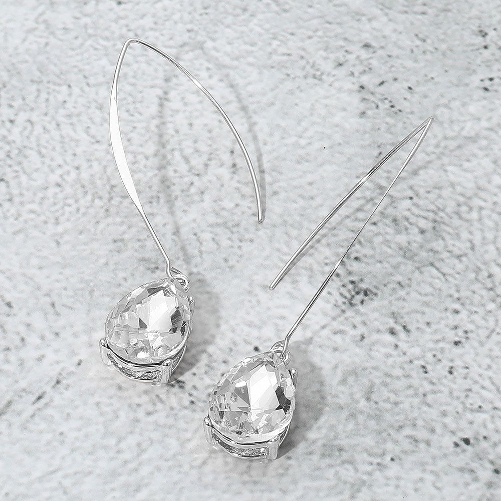 Silver earrings with clear gemstones on a textured gray surface