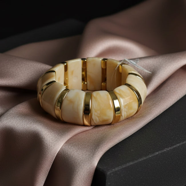 Beige and gold bracelet on a stone surface with a dark background