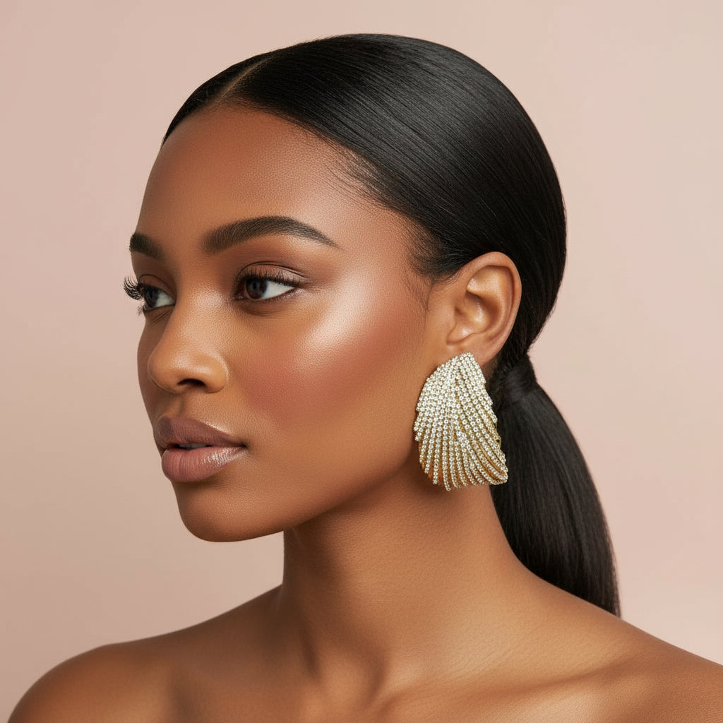 Woman wearing large, rhinestone dangling earrings with a neutral background