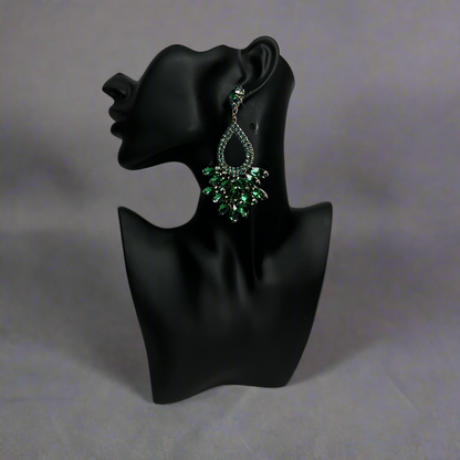 green rhinestone earrings on a black mannequin against a blackish gray background