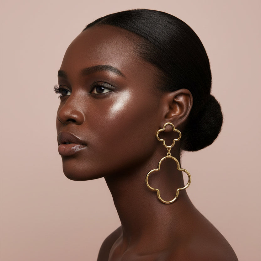 Woman wearing gold Oversized Hammered Metal Open Double Quatrefoil Link Earrings against beige background