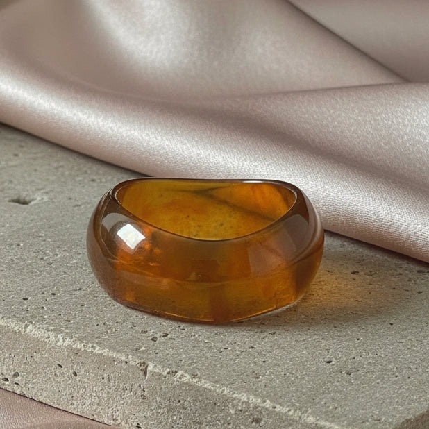 Amber-colored bangle on a textured surface with fabric in the background