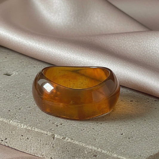 Amber-colored bangle on a textured surface with fabric in the background