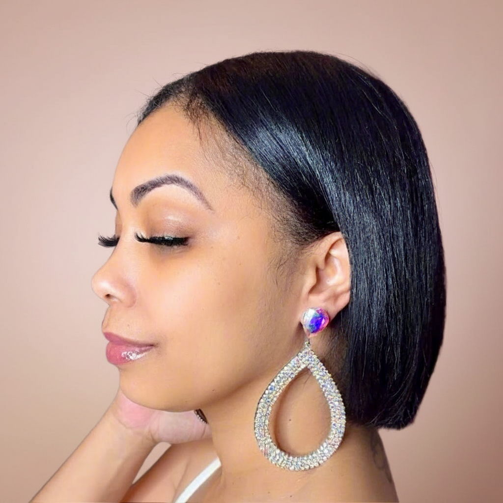 Woman wearing a large teardrop earring with a blush background