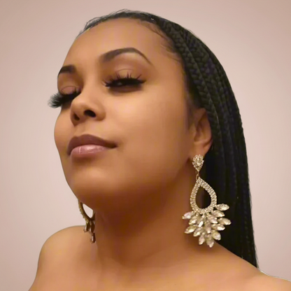 Woman wearing large, ornate earrings against a plain background