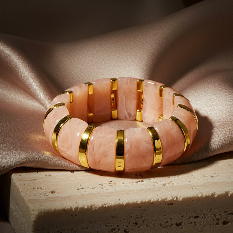 Decorative bangle with pink and gold bands on a gray surface