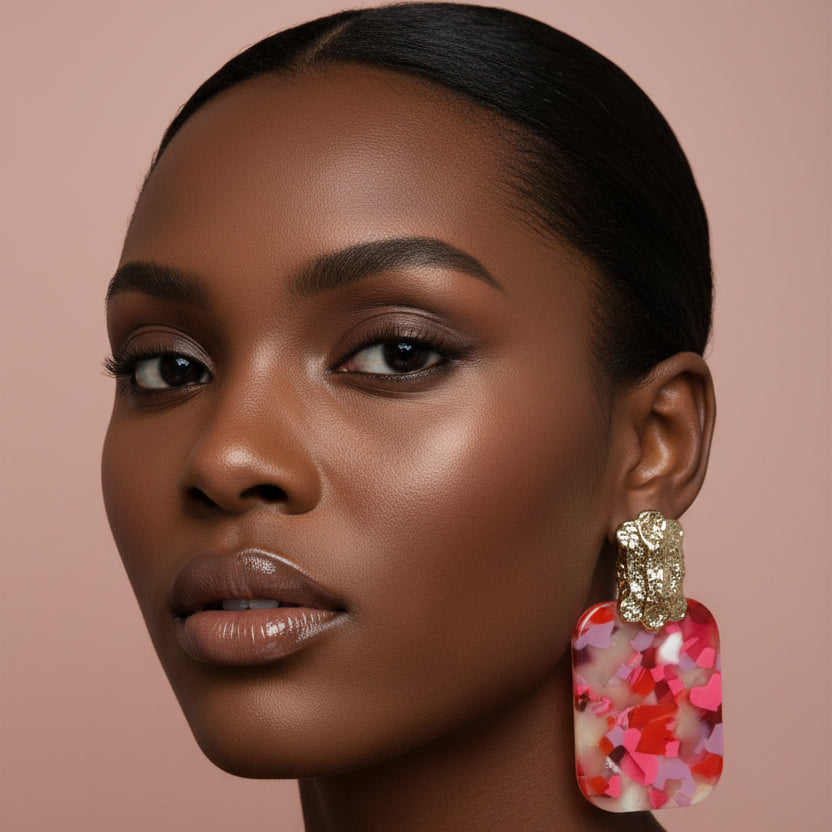 Woman wearing pink colorful earrings against a beige background 