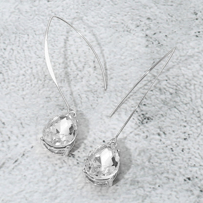Silver earrings with clear gemstones on a textured gray surface