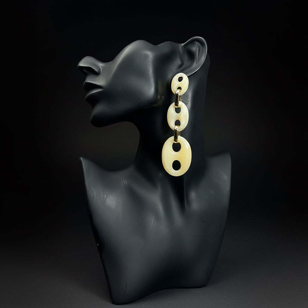 Pair of beige earrings on a black mannequin bust against a black background