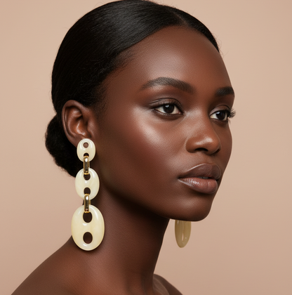 Woman wearing large, dangling earrings against a beige background