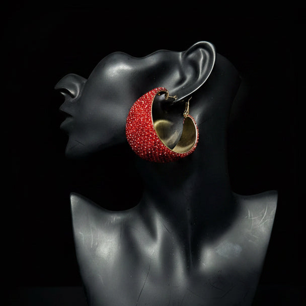 A large red beaded hoop earring with a gold-toned inner lining, displayed on a black female bust mannequin against a black background 