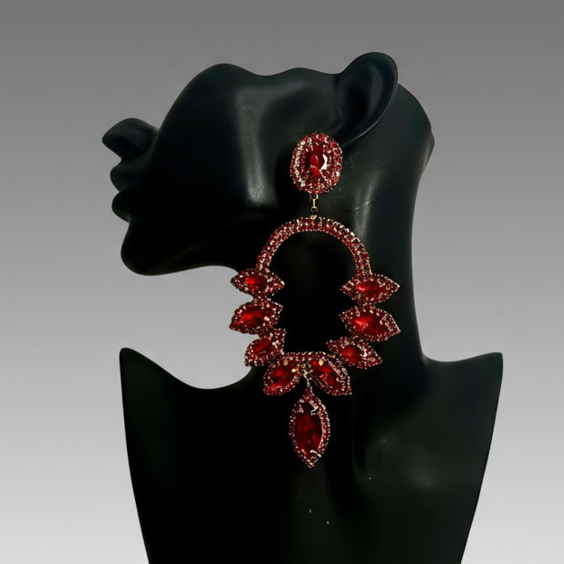 Red gemstone earrings on a black mannequin bust against a gray background