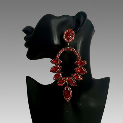 Red gemstone earrings on a black mannequin bust against a gray background