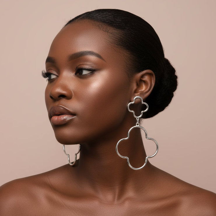 Woman wearing silver Oversized Hammered Metal Open Double Quatrefoil Link Earrings against beige background