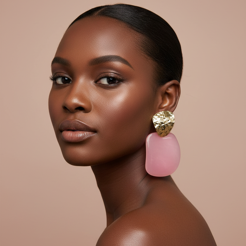 Woman wearing pink and gold earrings against a beige background