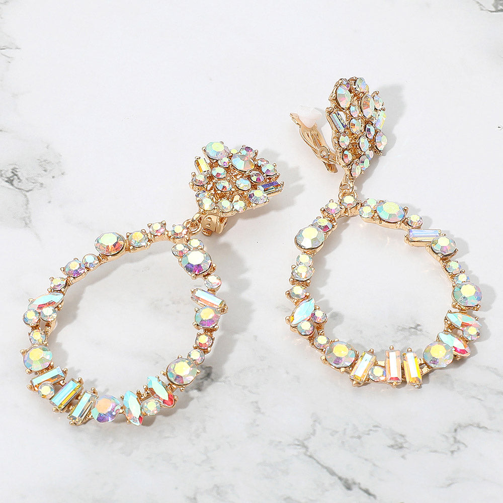 Gold hoop earrings with multicolored gemstones on a marble surface