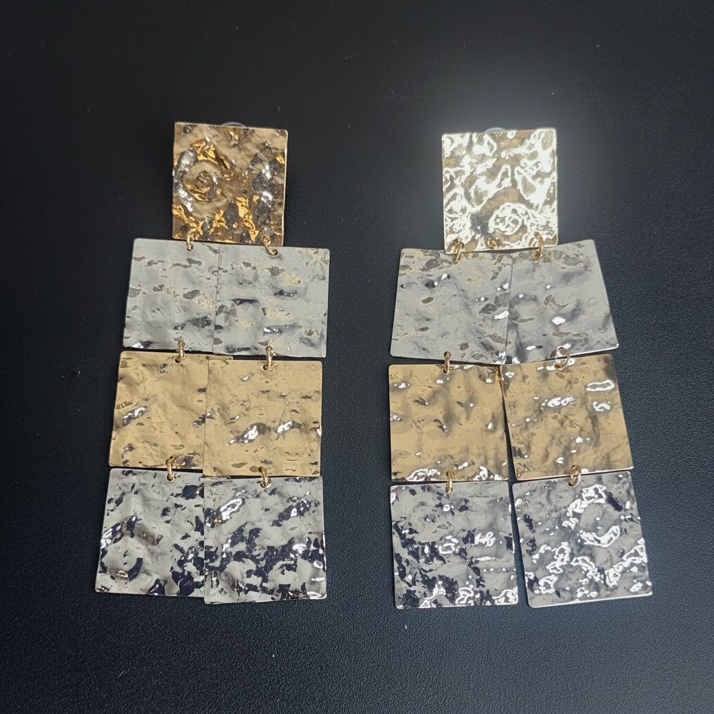 Pair of earrings with gold and silver squares,  on a dark background