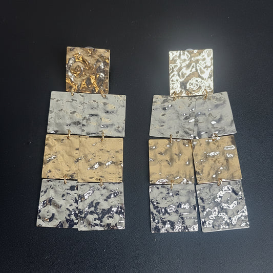 Pair of earrings with gold and silver squares,  on a dark background