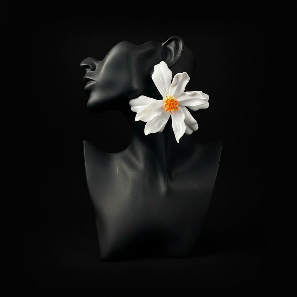 A glossy black sculptural bust of a woman's profile with a large white flower and orange center tucked behind her ear, set against a solid black background.