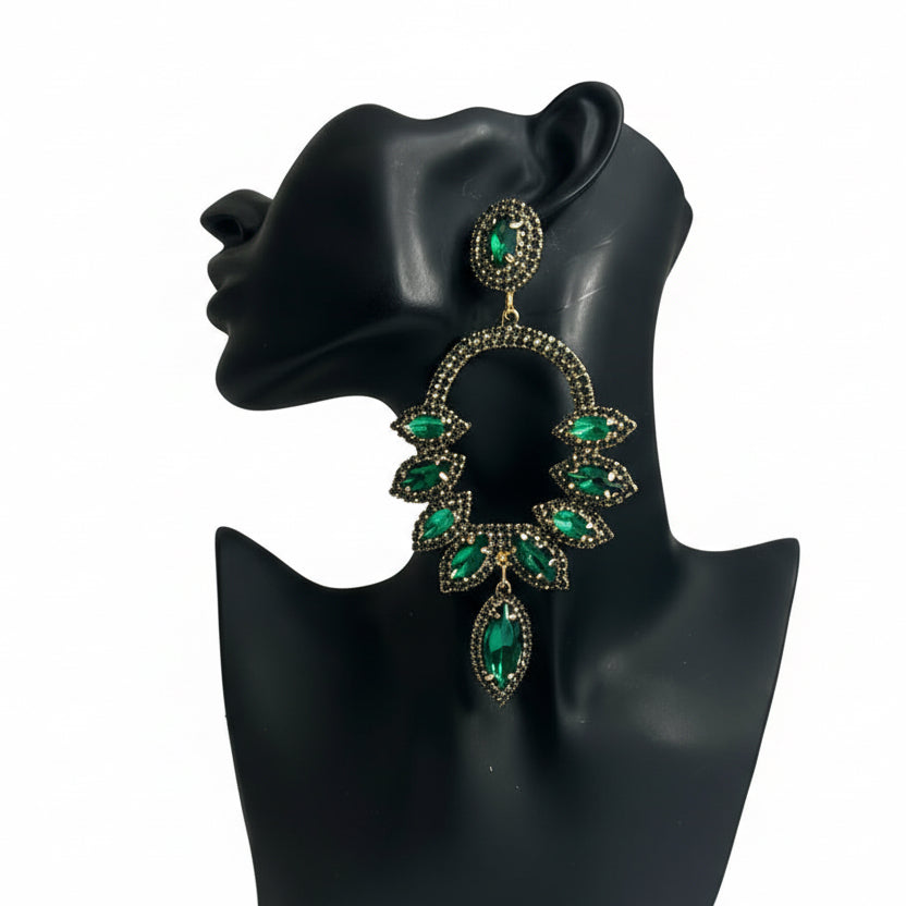 Green gemstone earrings on a black mannequin bust against a white background