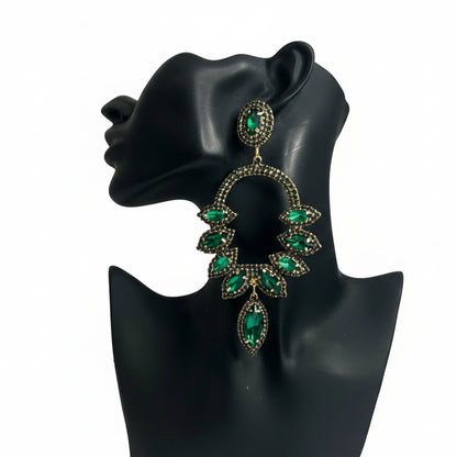 Green gemstone earrings on a black mannequin bust against a white background