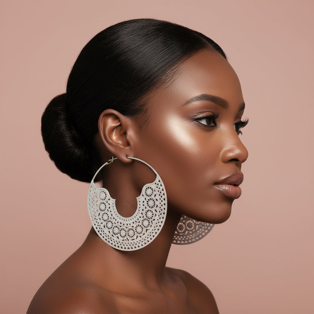 Woman wearing large oversized Silver hoop earrings with intricate designs against a beige background 